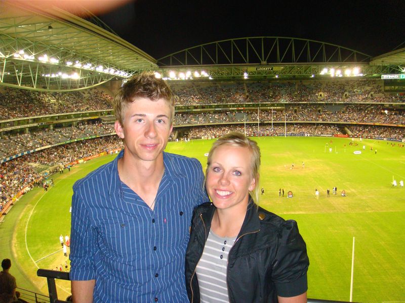 A young Daniel and Pernilla at a night-time sports stadium, the pitch lit up behind them