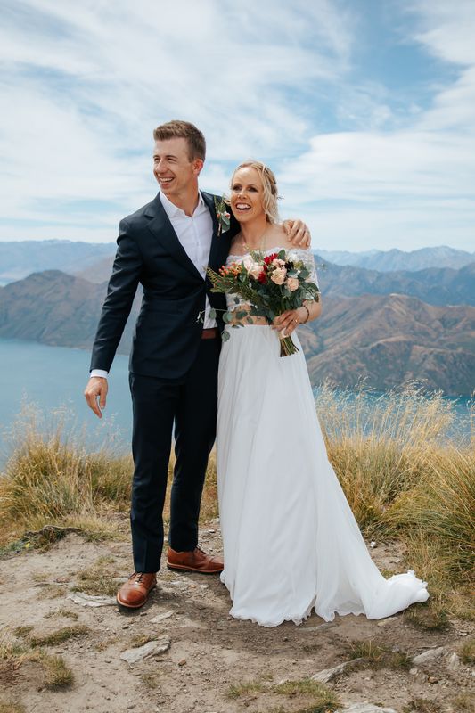 Daniel and Pernilla in wedding clothes on a mountainside above a lake