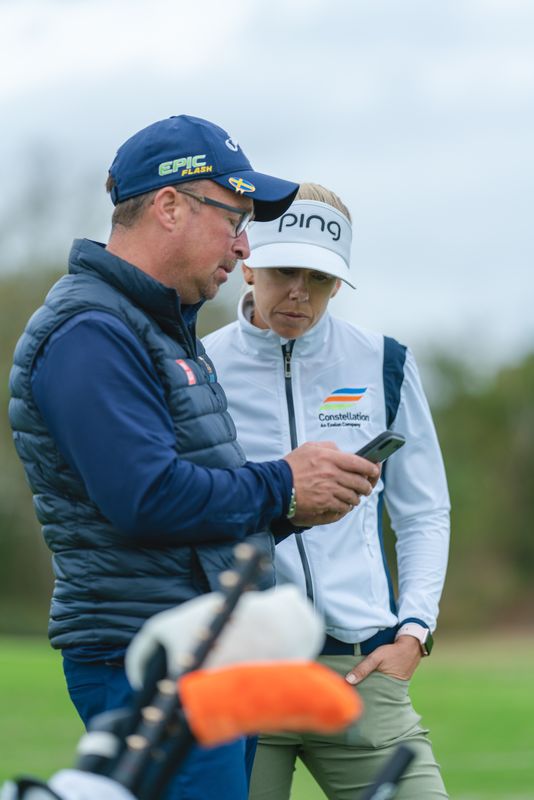 Pernilla Lindberg and coach Patrik Jonsson look at a phone together on the range